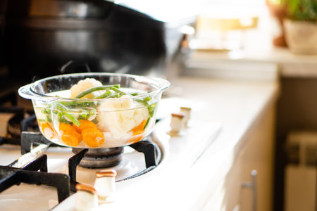 Transparent glass pan with vegetable soup, fresh hot food boils on the stove