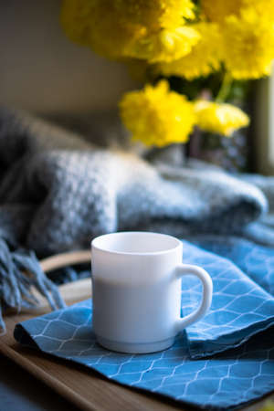 Black coffee in white mug with elegant blue napkin and yellow flowersの写真素材