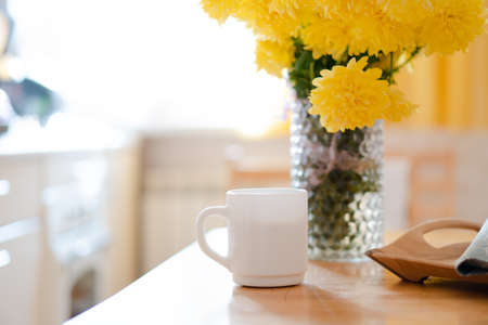 White coffee mug with napkin on table in real kitchen interior with bright natural sunlightの写真素材