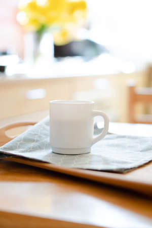 White coffee mug with napkin on table in real kitchen interior with bright natural sunlightの写真素材