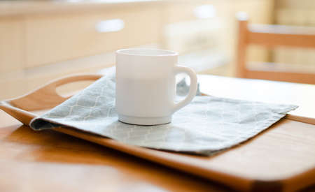 White coffee mug with napkin on table in real kitchen interior with bright natural sunlightの写真素材