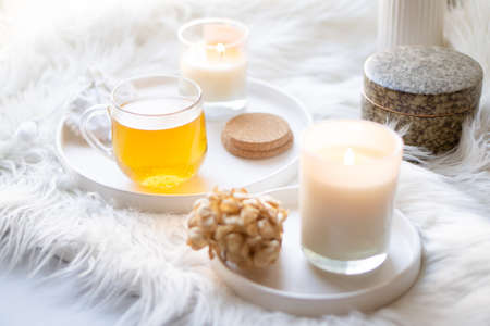 Cup of herbal tea and burning candle on round white decorative trayの写真素材