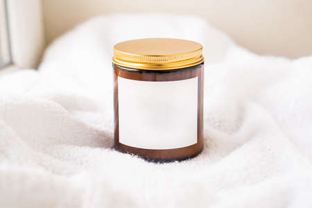 Amber glass jar with metal lid and blank label on white cotton fabric backgroundの写真素材