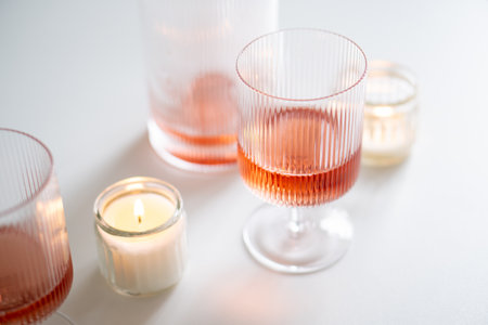 Rose wine in trendy ribbed wineglasses and decanter on white tableの写真素材