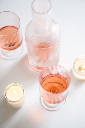 Rose wine in trendy ribbed wineglasses and decanter on white tableの写真素材
