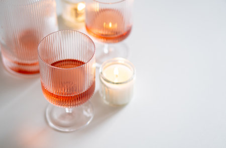 Rose wine in trendy ribbed wineglasses and decanter on white tableの写真素材