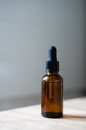 Amber glass serum oil dropper bottle on wooden table mock-up, cosmetic container daylight shotの写真素材