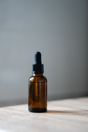Amber glass serum oil dropper bottle on wooden table mock-up, cosmetic container daylight shotの写真素材