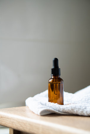 Amber glass serum oil dropper bottle and white towel on table mock-up, cosmetic container daylight shotの写真素材