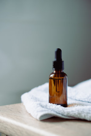 Amber glass serum oil dropper bottle and white towel on table mock-up, cosmetic container daylight shotの写真素材