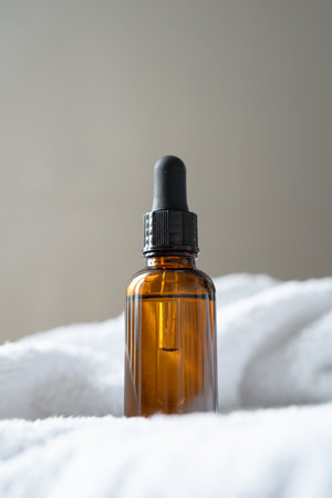 Amber glass serum oil dropper bottle and white towel on table mock-up, cosmetic container daylight shotの写真素材