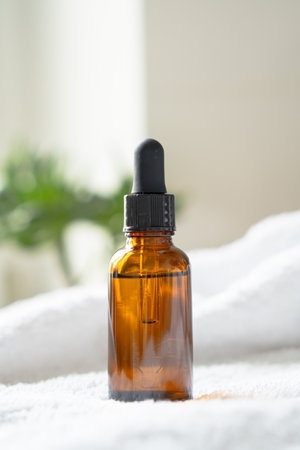 Brown amber glass serum oil dropper bottle and white towel on table mock-up, cosmetic container in real interiorの写真素材