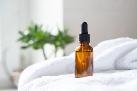 Brown amber glass serum oil dropper bottle and white towel on table mock-up, cosmetic container in real interiorの写真素材