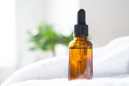 Brown amber glass serum oil dropper bottle and white towel on table mock-up, cosmetic container in real interiorの写真素材