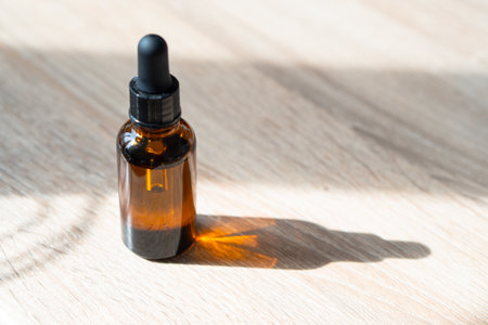 Amber glass serum oil dropper bottle on wooden table mock-up, cosmetic container daylight shotの写真素材