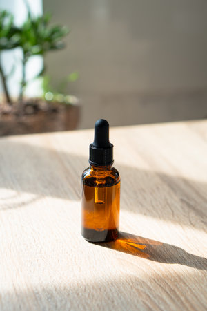 Brown amber glass serum oil dropper bottle and white towel on table mock-up, cosmetic container in real interiorの写真素材