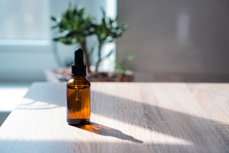 Brown amber glass serum oil dropper bottle and white towel on table mock-up, cosmetic container in real interiorの写真素材