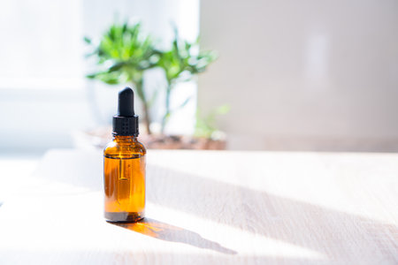 Brown amber glass serum oil dropper bottle and white towel on table mock-up, cosmetic container in real interiorの写真素材