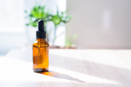 Brown amber glass serum oil dropper bottle and white towel on table mock-up, cosmetic container in real interiorの写真素材