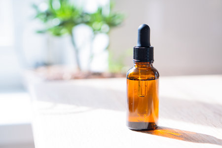 Brown amber glass serum oil dropper bottle and white towel on table mock-up, cosmetic container in real interiorの写真素材