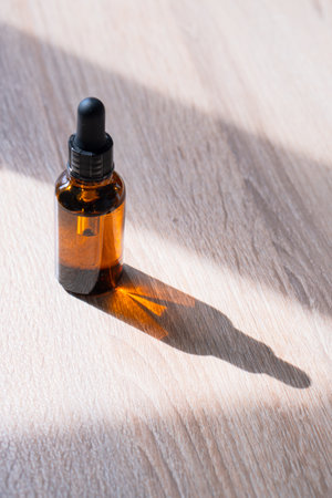Amber glass serum oil dropper bottle on wooden table mock-up, cosmetic container daylight shotの写真素材