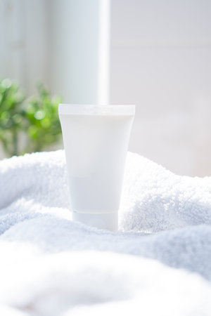 White cream tube and towel in real room interior mock-up, beauty and care product packaging templateの写真素材