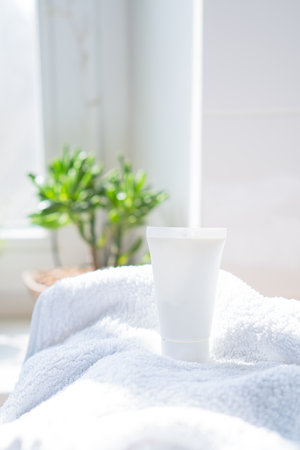 White cream tube and towel in real room interior mock-up, beauty and care product packaging templateの写真素材
