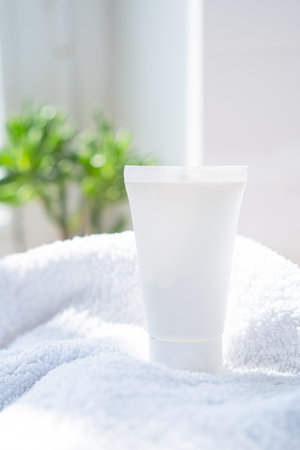 White cream tube and towel in real room interior mock-up, beauty and care product packaging templateの写真素材