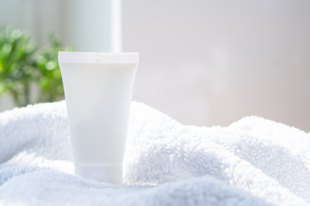 White cream tube and towel in real room interior mock-up, beauty and care product packaging templateの写真素材