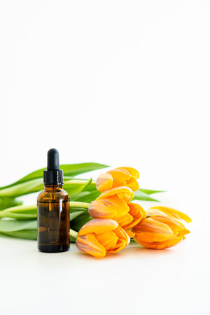 Amber glass cosmetic dropper bottle and orange tulips isolated on white background, serum bottle mockupの写真素材