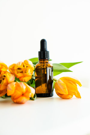 Amber glass cosmetic dropper bottle and orange tulips isolated on white background, serum bottle mockupの写真素材