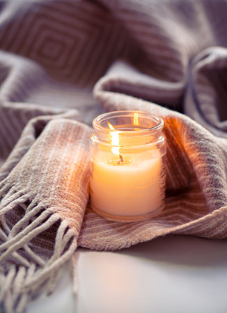 Enjoy the tranquil ambiance of a serene evening with cozy candlelight and a warm blanket fabricの写真素材