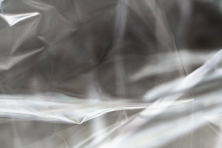 Crumpled clear plastic background, abstract glossy broken surface texture with creases
