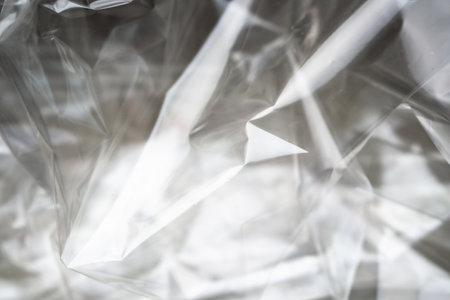 Crumpled clear plastic background, abstract glossy broken surface texture with creasesの写真素材
