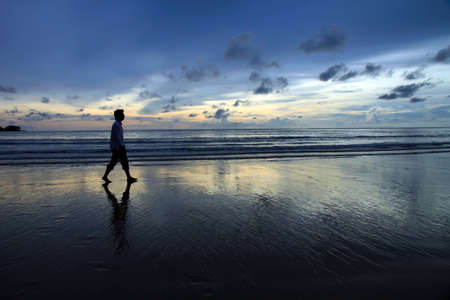 In a sunset scene, a man walks along Nai-yang beach Phuket / take on Sept 2010の写真素材