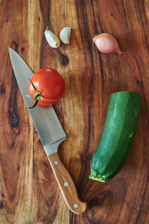 Chef's knife and vegetables on a wooden cutting board. Wooden chopping board with knife and vegetables.の写真素材