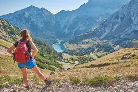 Hiking through the Bavarian alps. Hiker in front of the Soiernsee in the alps. Hiking through a panoramic mountain landscape in the alps.の写真素材