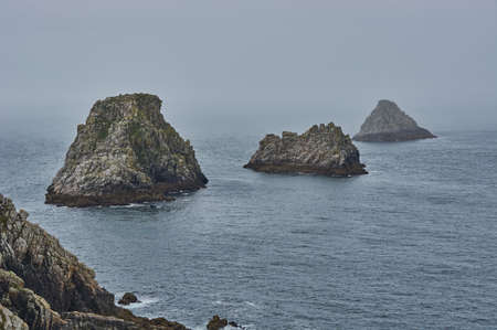 Mystical rock formation in the misty Atlantic ocean. Rocky islands at the coastline of Brittany, France.の写真素材