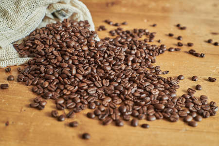 Closeup of espresso beans on a wooden vintage table. Coffee beans and coffee beans bag on a wooden table.の写真素材