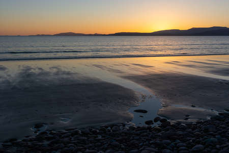 Sunset at a beach at the Ring of Kerry, Ireland. Colorful reflections in the wet sand, small stream flows into the sea.の写真素材