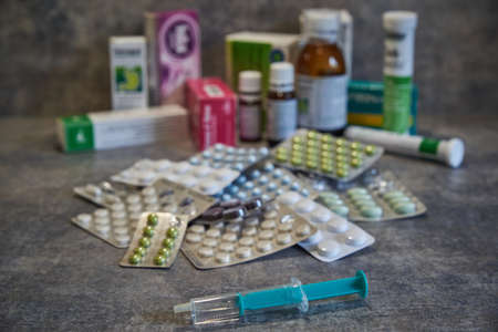 Closeup of a syringe and various pills in the background. Vaccine in a syringe. Collection of various drugs and pills.の写真素材