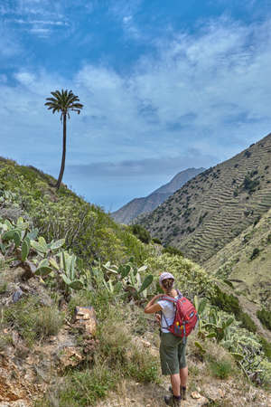 Hiking through the panoramic mountain landscape in La Gomera, Spain. Hiker in the mountains in La Gomera, Spain. View from the mountains on the ocean.の写真素材