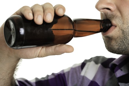 Casual young man holding bottle of beer, smiling. Isolated on white.の写真素材