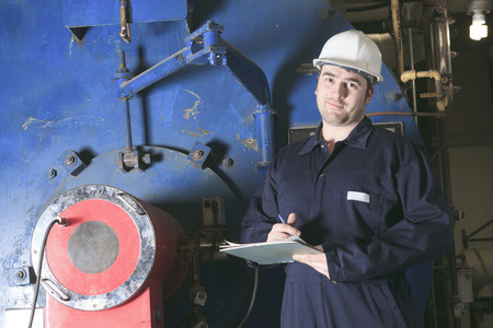 maintenance engineer checking technical data of heating system equipment in a boiler room