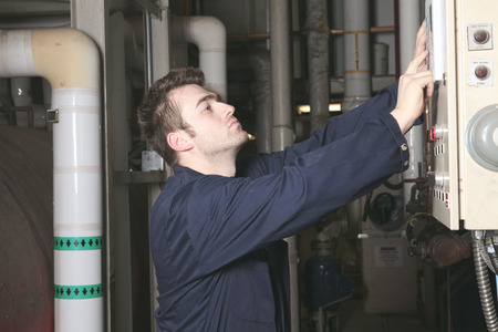 maintenance engineer checking technical data of heating system equipment in a boiler room