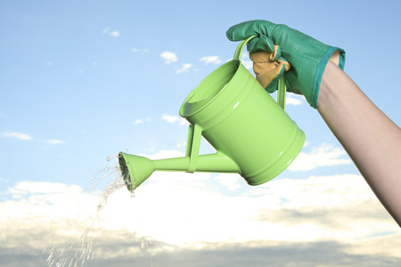 Green watering can on the hand of a girlの写真素材