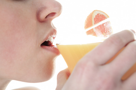 Healthy lifestyle - fitness woman drink juice smiling happy looking at camera. Pretty woman isolated on white .の写真素材