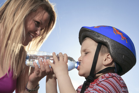 A boy drinking water outsideの写真素材