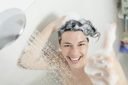 Shower woman. Happy smiling woman washing shoulder showering in bathroom.の写真素材