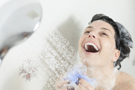 Shower woman. Happy smiling woman washing shoulder showering in bathroom.の写真素材